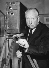 5058144 (900326) Alfred HITCHCOCK, britischer Regisseur, Portrait neben einer Filmkamera. "Jede Nutzung ist honorarpflichtig