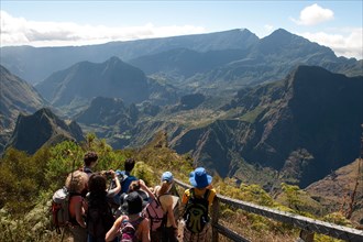 Hikers look down to the Mafate Cirque at a viewpoint on the Maido Peak.