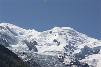 Paraglider on final approach with Mont Blanc in the background. Chamonix, Haute-Savoie, Auvergne-Rhone-Alpes, France.