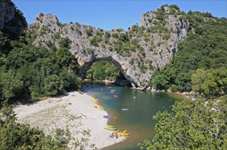 Pont d’Arc rock archway over the Ardeche river Gorges d’Ardeche Gard France with canoes and tourists sunbathing