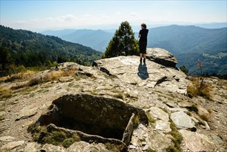 Walker by ancient burial site on the Fontmort hills on the Robert Louis Stevenson Trail in the Cévennes, Lozère, France