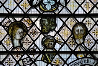 England. Ely Cathedral. Stained glass. man . woman. lead in diamond pattern . floral areas of pattern. yellow. black. writing.