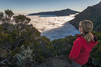 Young woman overlooking a sea of ??clouds above Cilaos basin, Cirque de Cilaos, Reunion, Africa