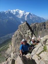 Boy and father rock climbing on a sunny day in the alps.  Mont Blanc is in the background.