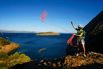 climber throwing a rope at coastal rock Bec de l'Aigle, adventure way, France, Provence, Calanques National Park, La Ciotat