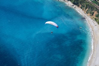 AIR-TO-AIR VIEW. Paramotor flying above the Blue Gulf of Roquebrune-Cap-Martin. Alpes-Maritimes, French Riviera, France.