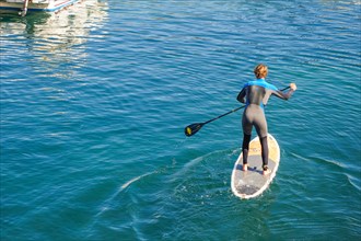 Man paddle boarding, Paddleboarding, out of old port of Biarritz, France.
