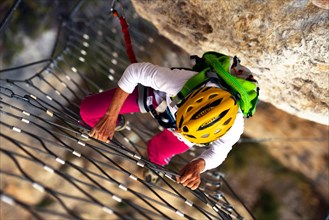 climber at a rock wall with steel net, Via ferrata Escale a Peille, France