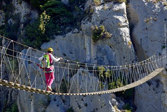 female climber on hanging bridge, via ferrata Escale a Peille, France, Caire, Peillon