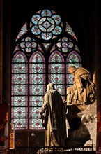 Beautiful stained glass window and sculpture inside the Notre Dame Cathedral, Paris, France.