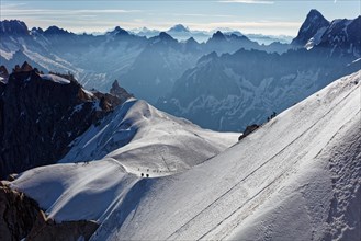 Chamonix, south-east France, Auvergne-Rhône-Alpes. Climbers heading for Mont Blanc. Descending from Aiguille du Midi cable car station towards sunny s