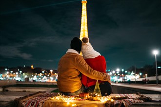 Two lovers contemplating Eiffel Tower during Christmas night