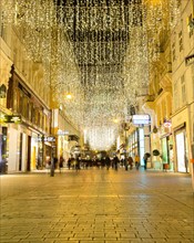 VIENNA, AUSTRIA - 2ND DECEMBER 2015: A view along Kohlmarkt at night during the Christmas season. People can be seen.