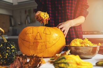 woman prepare pumpkin for halloween holiday decoration remove seeds at home kitchen