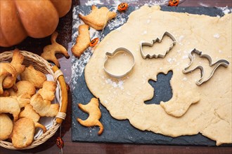 Making cookies for Halloween. Cut out cookies from dough in the form of pumpkin, cat, ghost and bat.