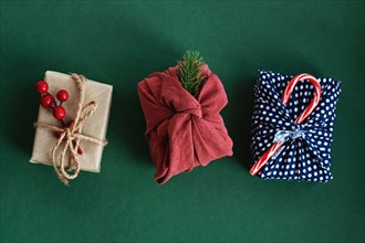 Christmas gifts wrapped in red textile with decor. Sustainable gifts. Zero waste. Xmas eco holiday. Traditional Japanese Furoshiki style. View from above. Flat lay.