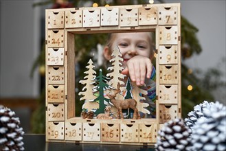 A girl opens wooden advent calendar with presents