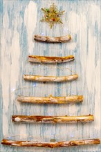 An original alternative to the Christmas tree made of wooden branches, decorated with a garland on a blue-white background.