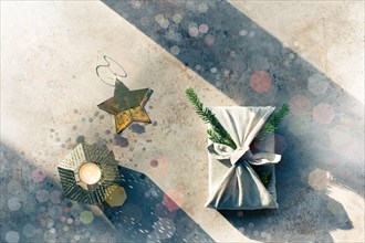 Furoshiki style gift for Christmas or New Year on a white background with bokeh. Flat lay with candle and star.