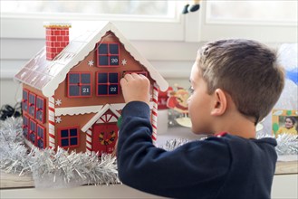 young caucasian boy looking for a surprise in the advent calendar at home