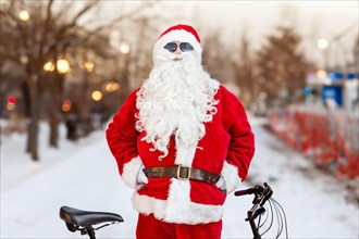 Young cool Santa Claus standing with his bicycle