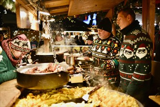 Cooks preparing sausages & other items in outdoor food stands at the Tallinn Christmas Market in Medieval Old Town of Tallinn, Estonia