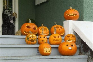 Humorous carved Halloween pumpkins displayed on the wooden front stairs of a house