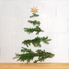 Homemade Christmas decoration made of natural branches nailed horizontally to the wall and a paper star as a top, simple and sus