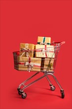 Shopping cart with Christmas gift boxes on red background