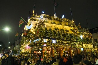 London, UK. 14th November, 2024. The Churchill Arms in Kensington switches on its festive light display with the external walls covered in over 80 Christmas trees and decorations. The pub attracts man...