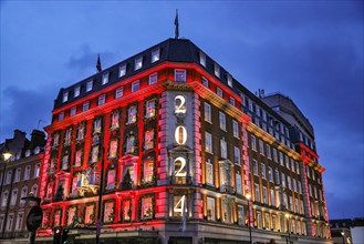 London, UK. 18th Nov, 2024. The annual 'advent calendar' facade decorations and 2024 display glows in festive red on the Fortnum and Mason building in Piccadilly. Christmas Lights, baubles and elabora...