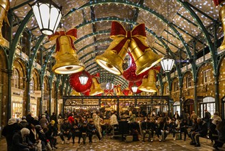 London, UK. 01st Dec, 2024. The former market halls of Covent Garden are decorated with giant bows and baubles as shoppers search for Christmas Presents in shops and along the small stalls of the cove...