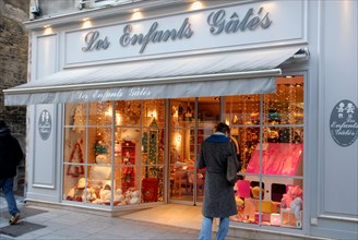 Woman,Outside Les Enfants Gates, Children's Toy Shop, Decorated for Christmas, Caen. Normandy, France. December