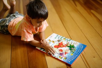 Six year old boy lies on floor and opens doors to advent calendar