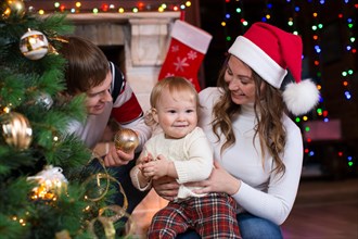 Happy family with child decorating Christmas tree in front of fireplace  in living room