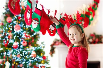 Kids opening Christmas presents. Child searching for candy and gifts in advent calendar on winter morning. Decorated Christmas tree for family with ch