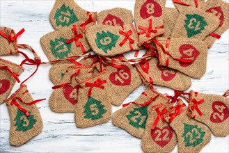 Advent calendar, on a light, wooden background lie plaited bags with days on the calendar, free space for text