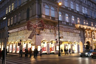 Vienna, Austria - 6th January 2017: Street corner near Opera theaterwith big bright decoration red bow on facade of old historical building in Vienna center at night