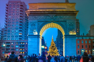 New York City, NY / USA - 12 25 2013: People are walking during Christmas time at Washington Square in Manhattan at night in front of Christmas tree