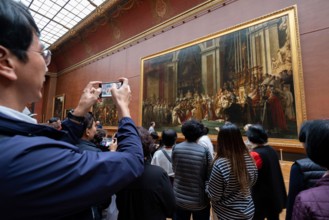 Crowd of asian tourists in front of The Coronation of Napoleon oil painting at the Louvre Museum in Paris, France, Europe