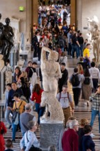 Rear view of thDying Slave marble sculpture by Italian Renaissance artist Michelangelo on a crowded room at the Louvre Museum in Paris, France, Europe