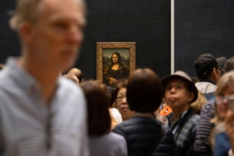 Crowd of tourists queuing to take pictures of the Mona Lisa painting by italian artist Leonardo da Vinci at the Louvre Museum in Paris, France, Europe