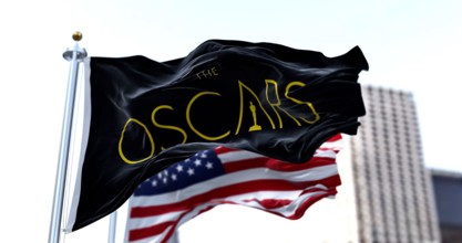 Hollywood, CA, USA, March 2022: the flag with the Academy Awards logo waving with the American flag blurred in the background. The Academy Award, aka