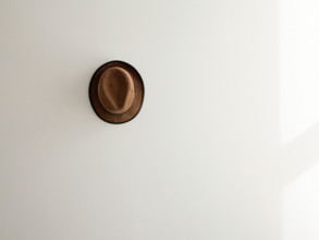 lone brown corduroy hat on white wall.