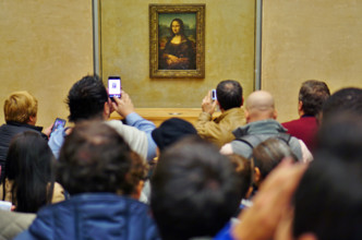 Visitors take selfie pictures on their phones in front of the Mona Lisa (La Joconde) painting by Leonardo da Vinci in the Louvre