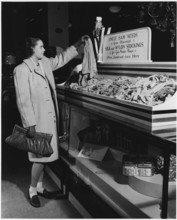 Part of a campaign to collect used nylon stockings for American efforts during World War II, a young woman holds up a pair of disbanded stockings that will be recycled into gun powder bags, 1942. Imag...