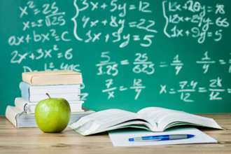 School textbooks on a desk in front of blackboard