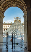 Looking through an archway towards the Pyramid at the Louvre in Paris France.  A former fortress and palace, The Louvre is the largest art museum in t