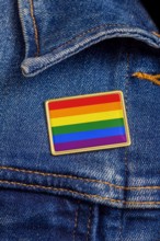 Gay pride flag pin on a denim jacket for LGBTQ identity, pride, and activism. The flag design is public domain for all uses.