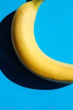 Creative minimal food – yellow banana on blue background. Organic natural fruit concept
